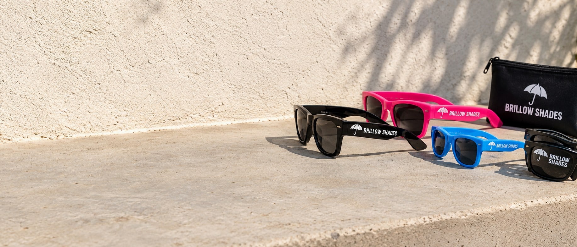 Custom printed promo sunglasses and neon party shades on a pale concrete ledge